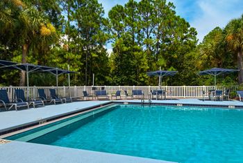 Resort-style pool with chaise lounges and umbrellas.